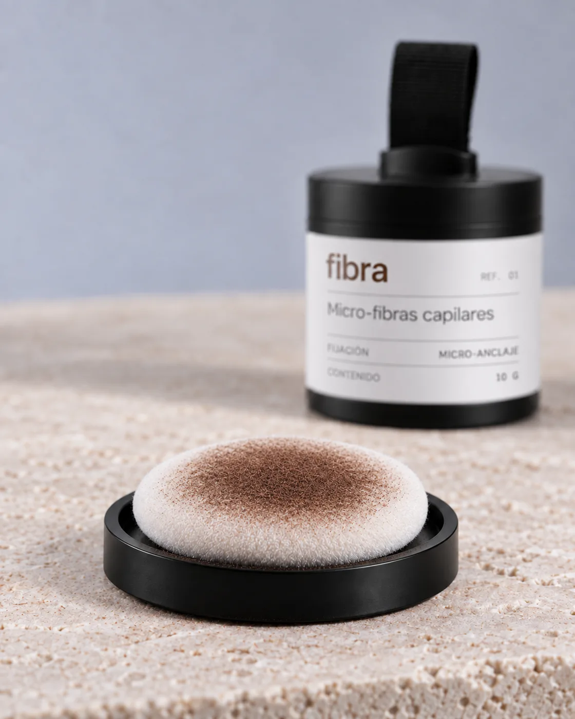 Aplicador de fibra con micro-fibras en tono castaño, junto al frasco